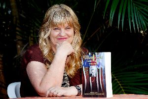 Author Barbara Miller in her tropical garden with her book on William Cooper